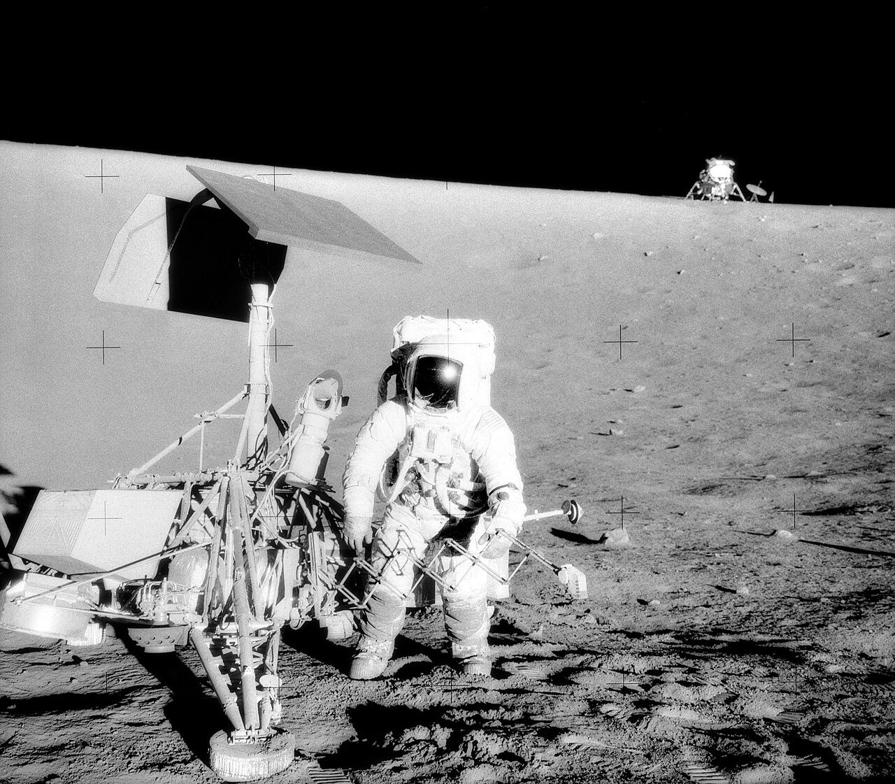 An astronaut in a white spacesuit stands beside the spindly Surveyor 3 spacecraft on the gray lunar surface, with a lander tiny on the horizon.