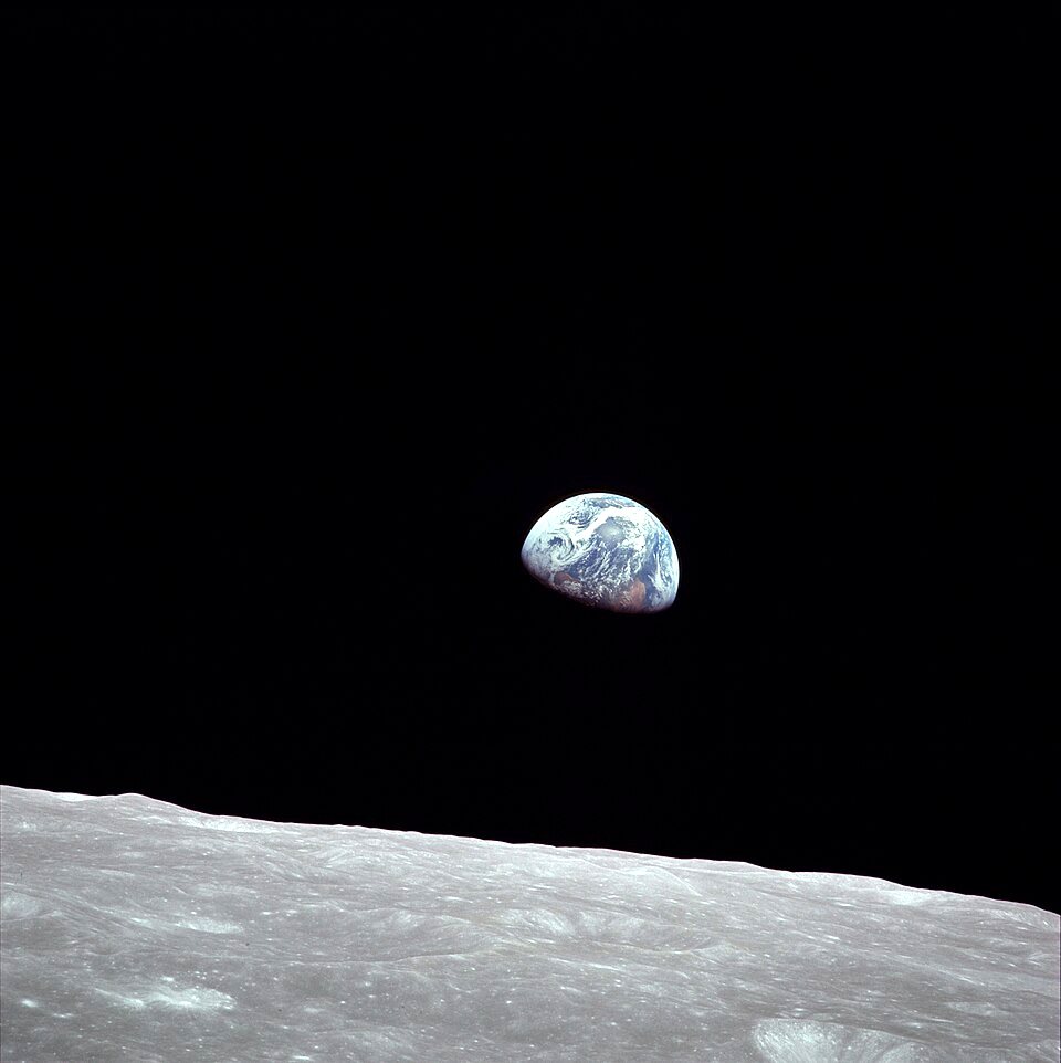 A small blue and white Earth hangs above the gray lunar horizon in a black sky.