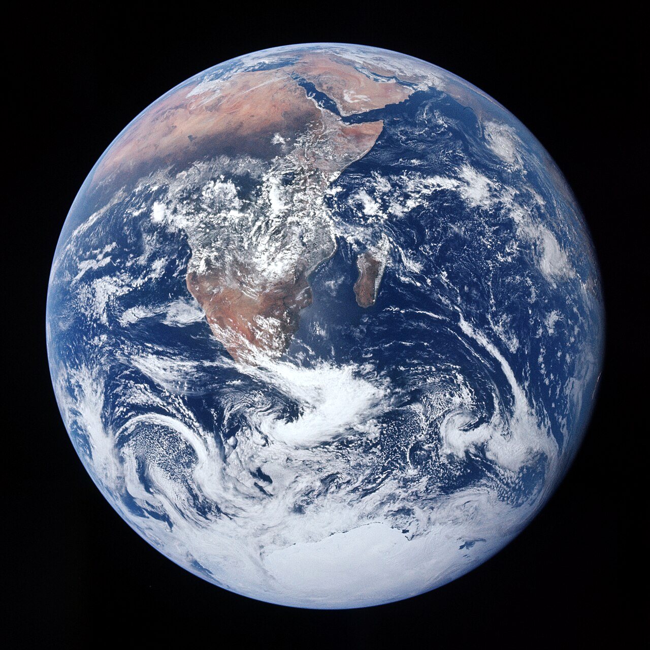 The whole Earth, a blue sphere swirled with white cloud, with Africa at the top and the Antarctic ice cap at the bottom, against black space.