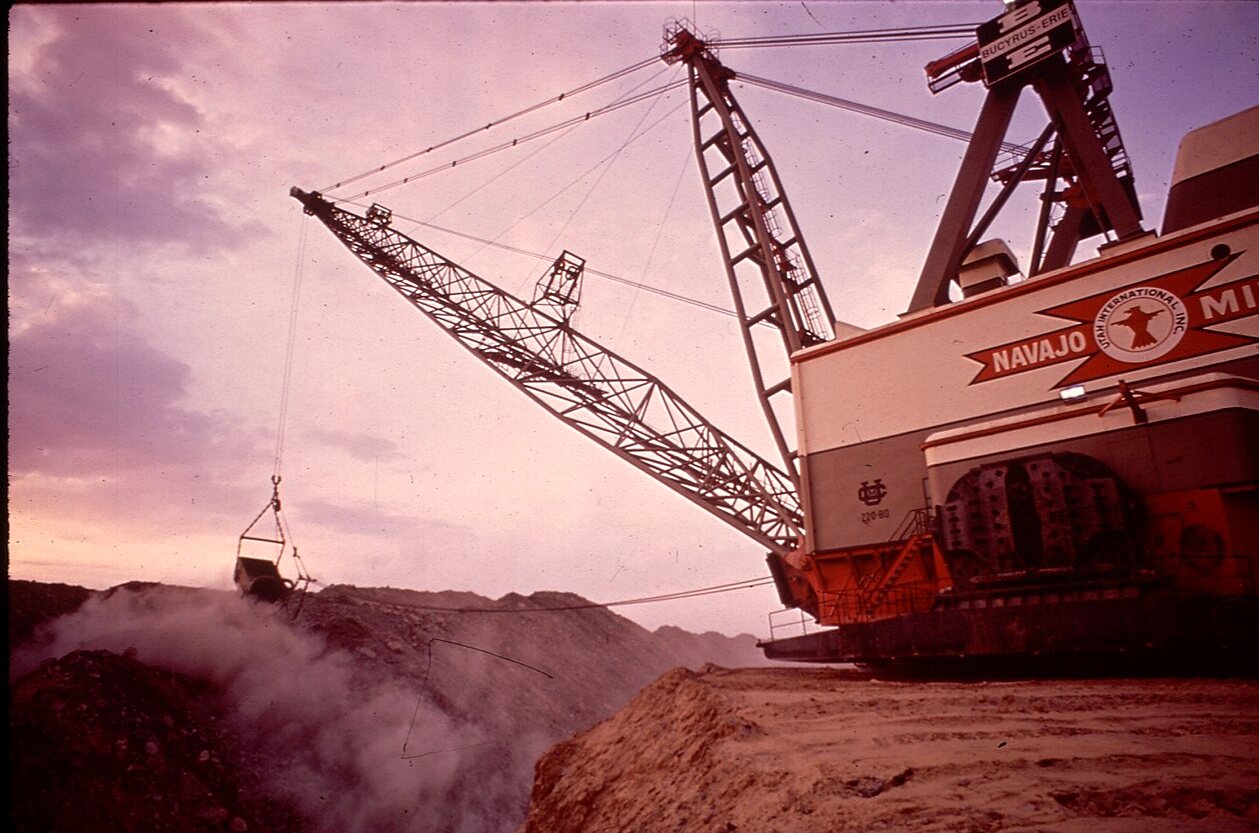 A dragline excavator with its boom over a strip-mine pit at dusk, its cab lettered Navajo Mine.