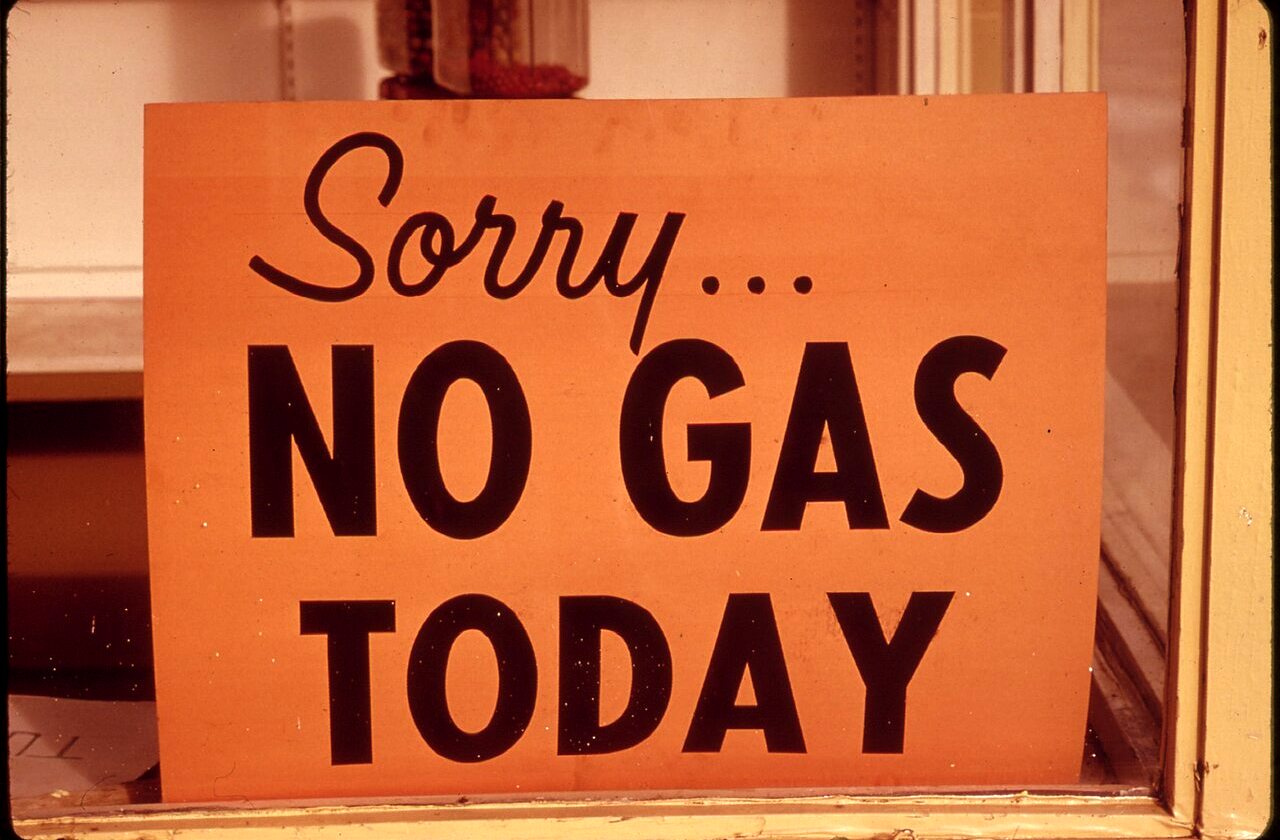 An orange hand-lettered sign in a window that reads Sorry... No gas today.