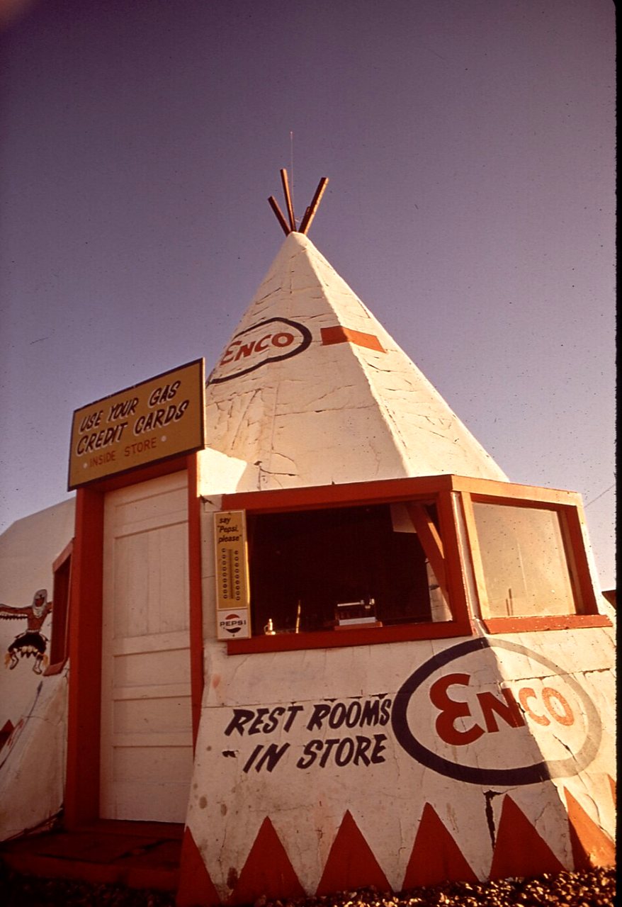 A white tepee-shaped gas station with an Enco sign and the words Rest rooms in store painted on its base.