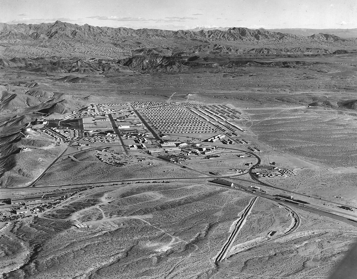 An aerial view of Boulder City, Nevada, a planned grid of buildings and roads in a wide desert valley.