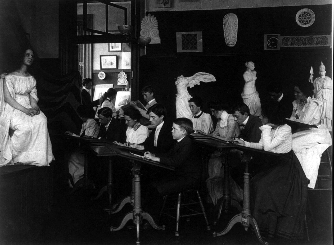 Students draw at tilted tables while a young woman in a white dress sits posed at left and plaster casts of statues line the shelves behind them.